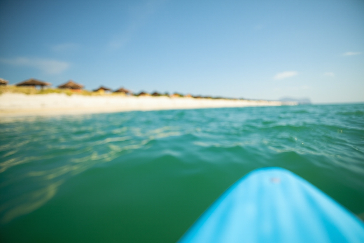 A paddleboard gliding over clear green water near a long sandy city beach